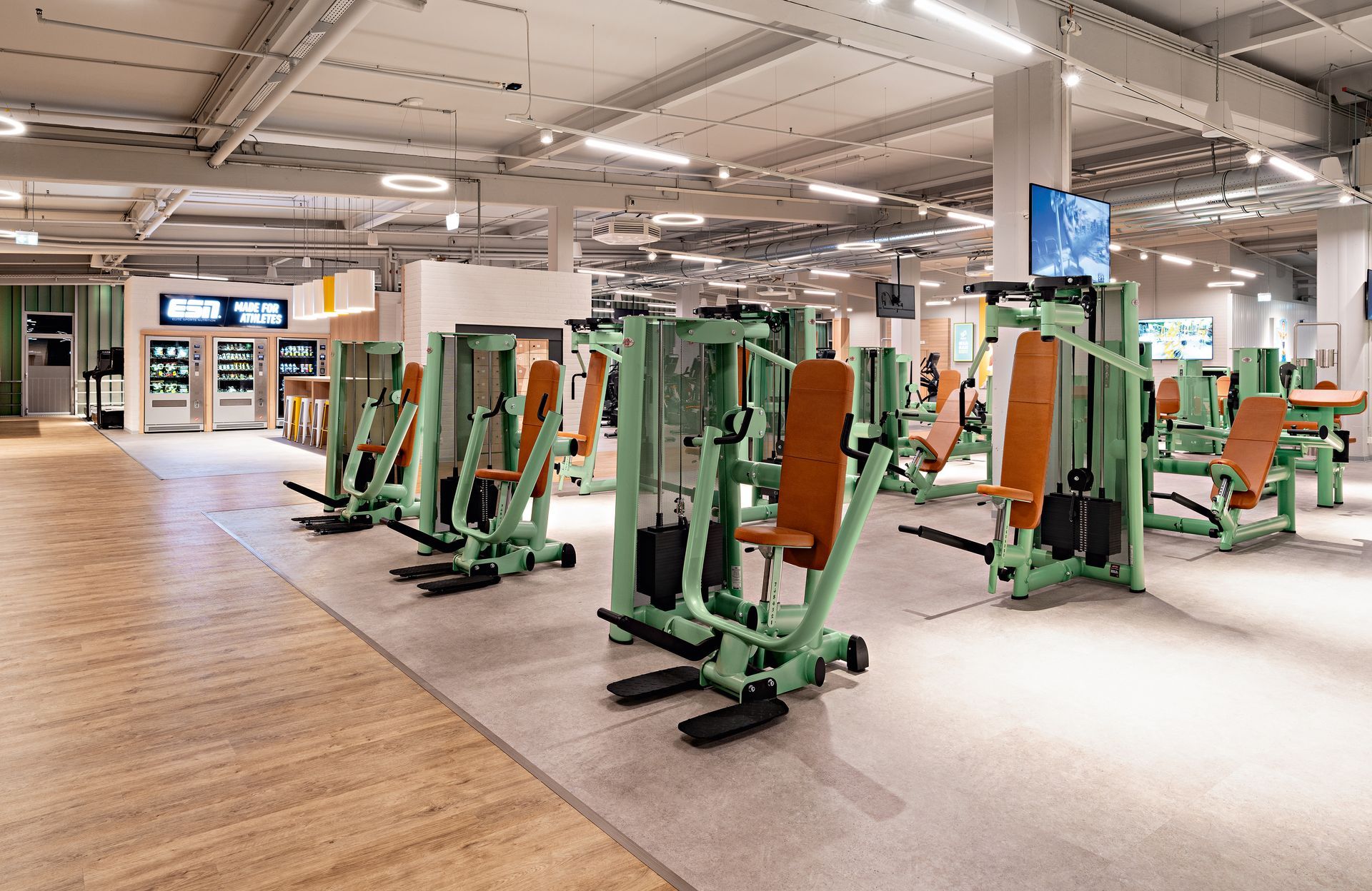 Innenausbau Fitnessstudio McFIT München Laim - Moderner Trainingsbereich mit Fitnessgeräten und graue PVC-Fliesen - Referenzprojekt Fitnessstudio Innenausbau Generalunternehmer