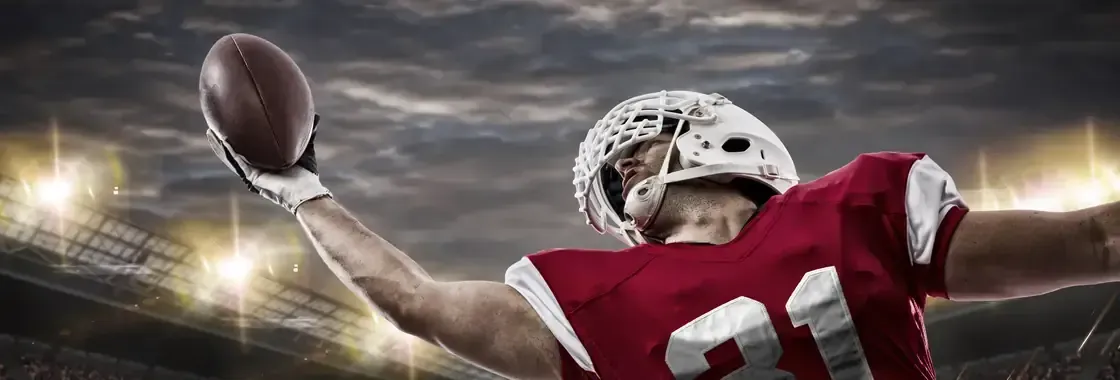 A football player catching a pass under stadium lights