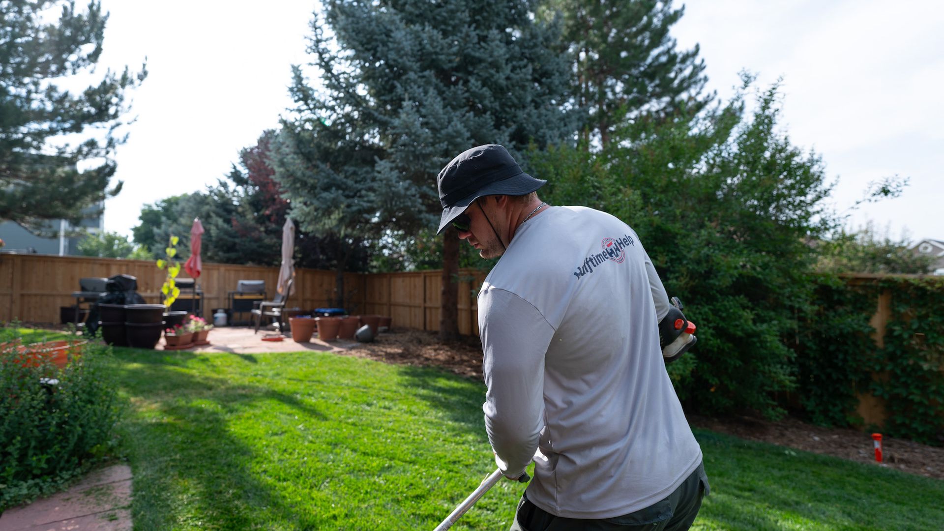 A man is using a lawn mower to cut the grass in a backyard.