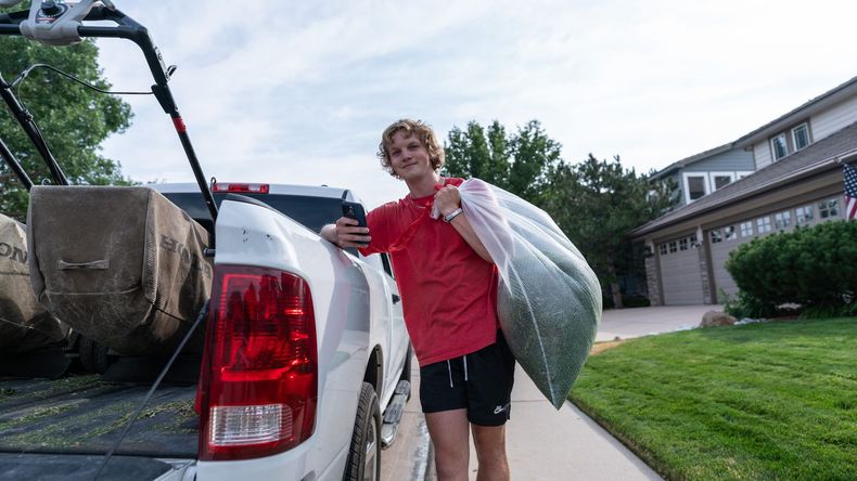 A young man is loading hay into the back of a truck.
