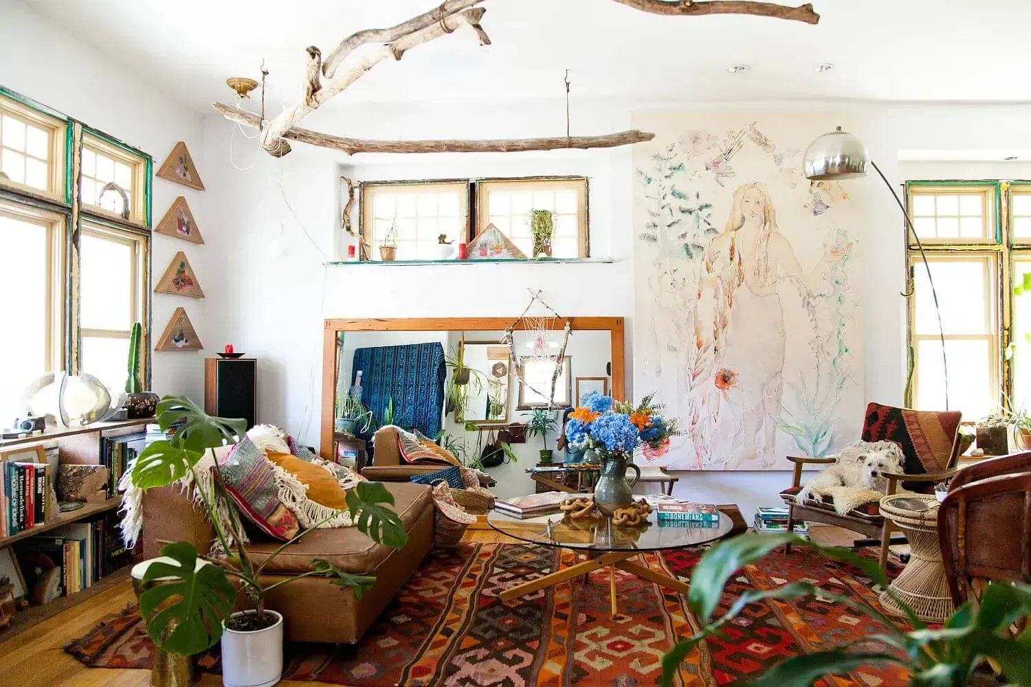 Un living plin cu mobilier , plante si un tablou pe perete.