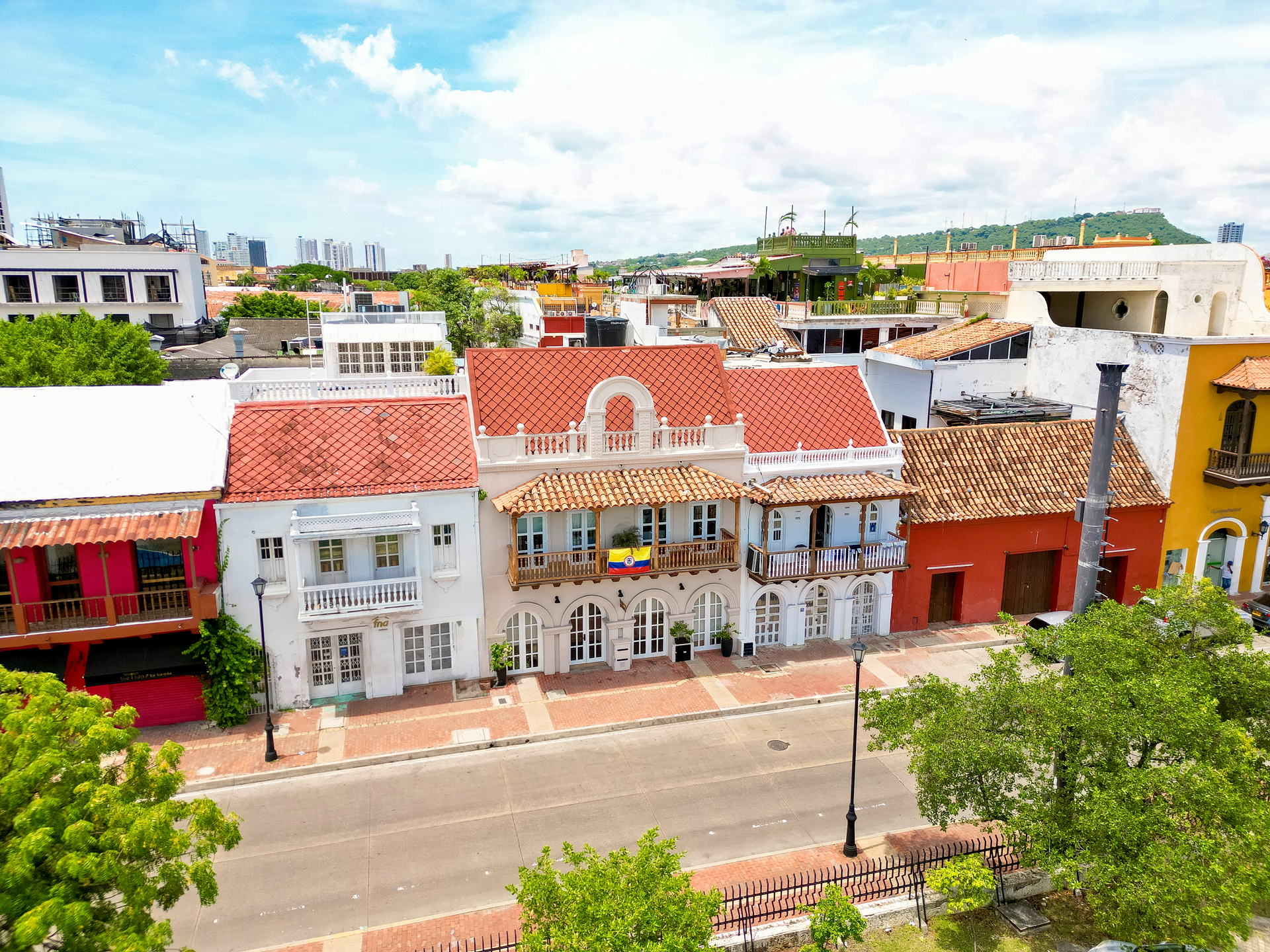 Row of colorful colonial buildings in Cartagena, Colombia, with red-tiled roofs and balconies, viewed from above on a sunny day.