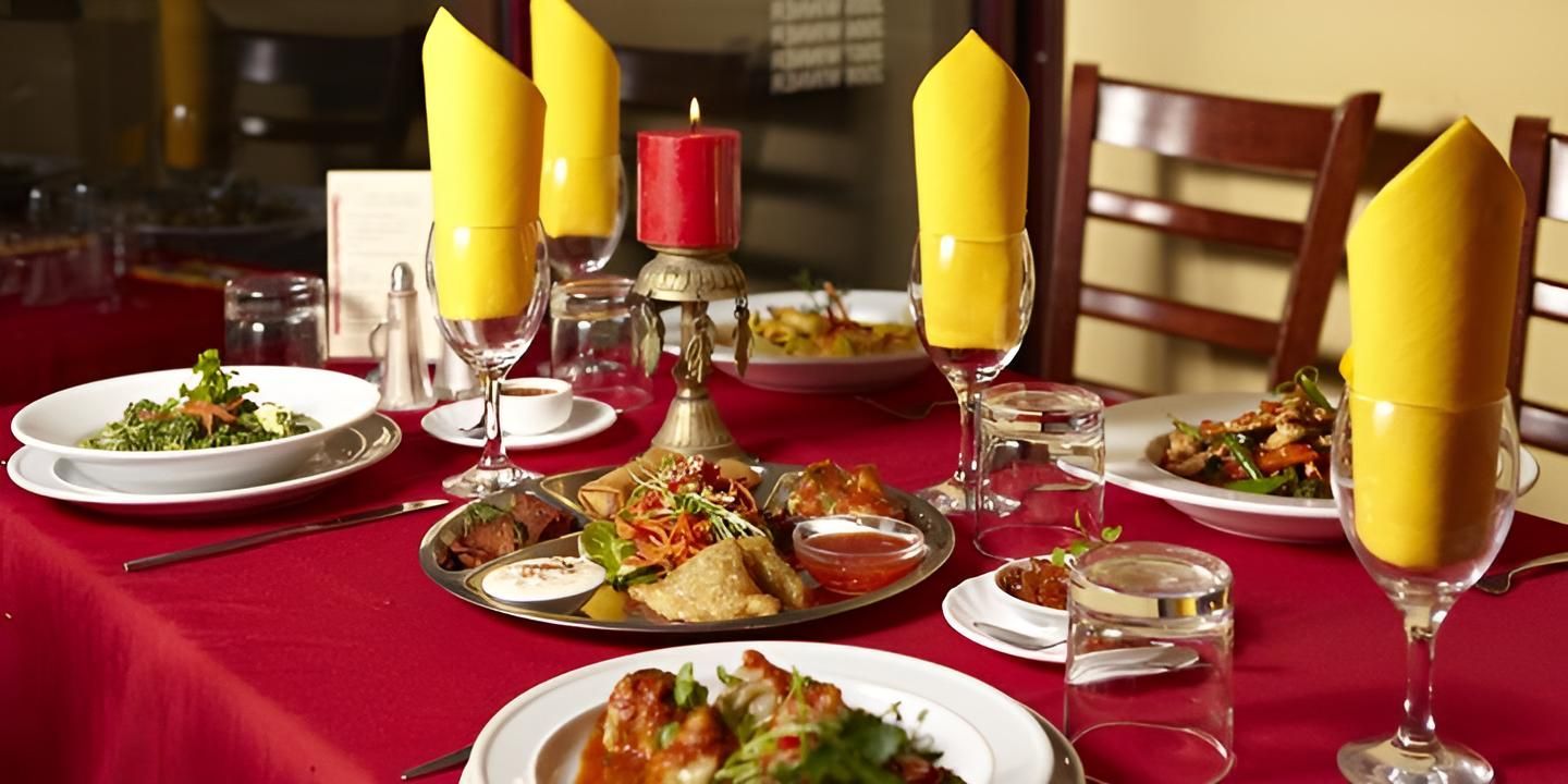 Table With Plates of Food and Yellow Napkins on It — Kathmandu Kitchen in Kingscliff, NSW