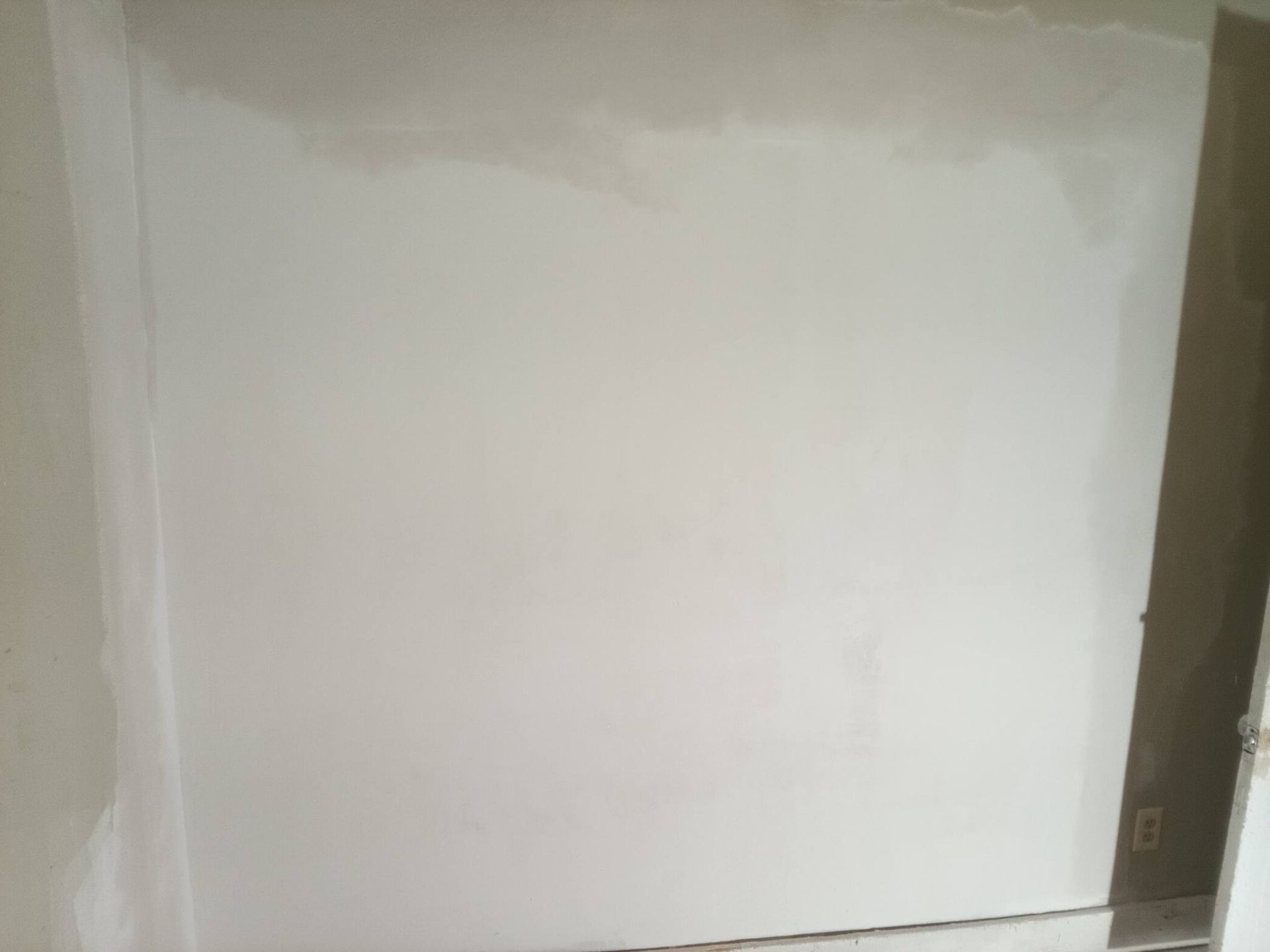 White painted wall with unfinished edges and a dark corner on the right