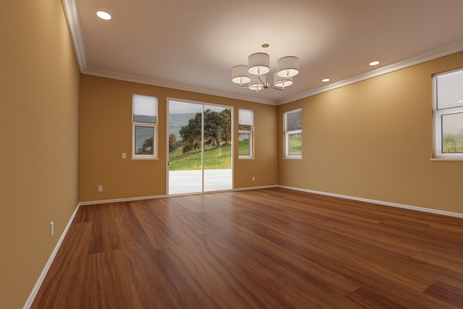 Empty tan living room with hardwood floors, chandelier, and sliding glass doors to a green yard