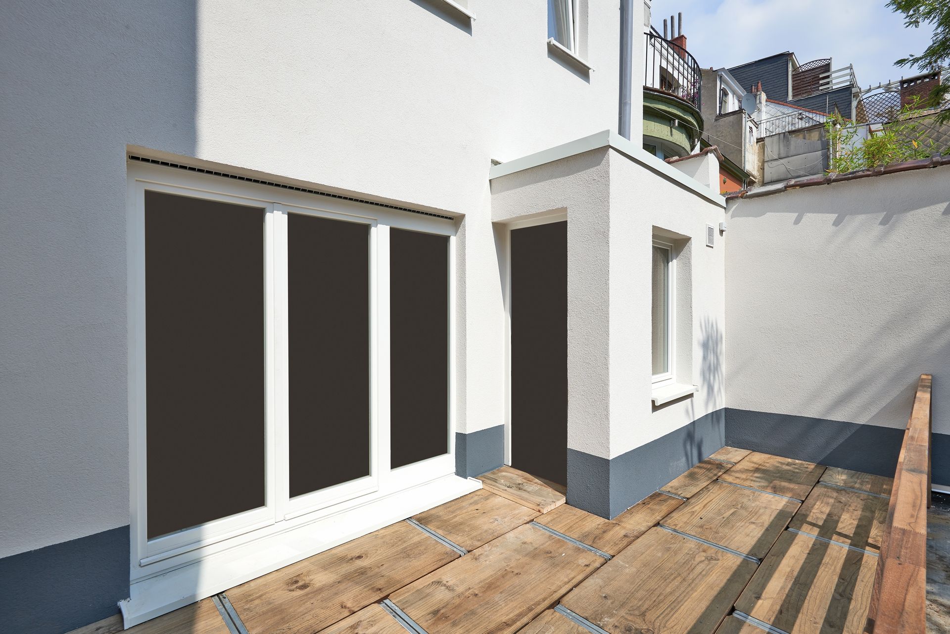 Modern white house patio with wood deck, sliding glass doors, and a small side window