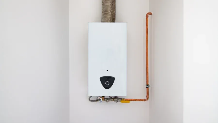 White wall-mounted boiler with copper pipes in a plain utility room