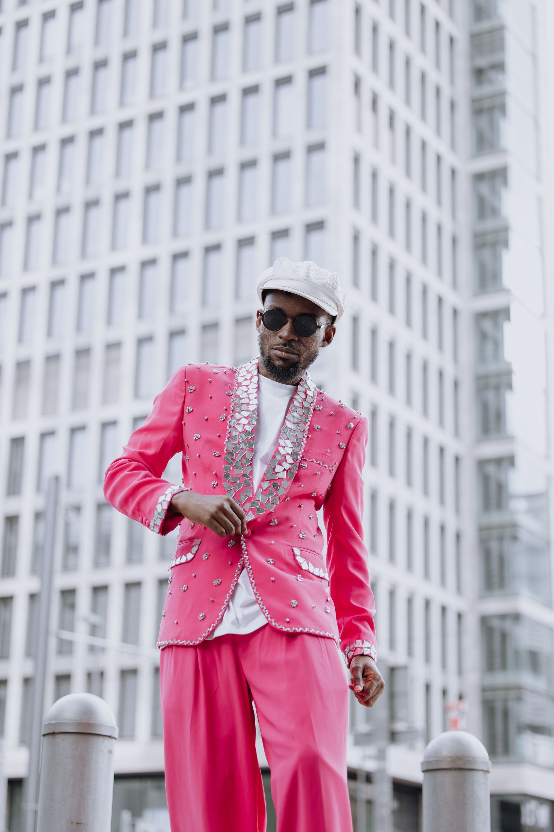 Man in bright pink suit posing outdoors in front of a tall office building