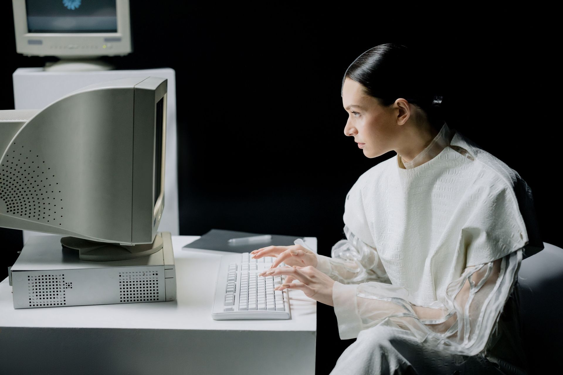 Person in white uses a desktop computer at a desk in a dark room
