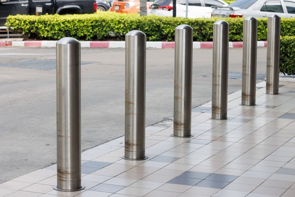 A row of stainless steel poles are lined up on a sidewalk. — On The Spot Steel Fabrication in Caloundra West, QLD