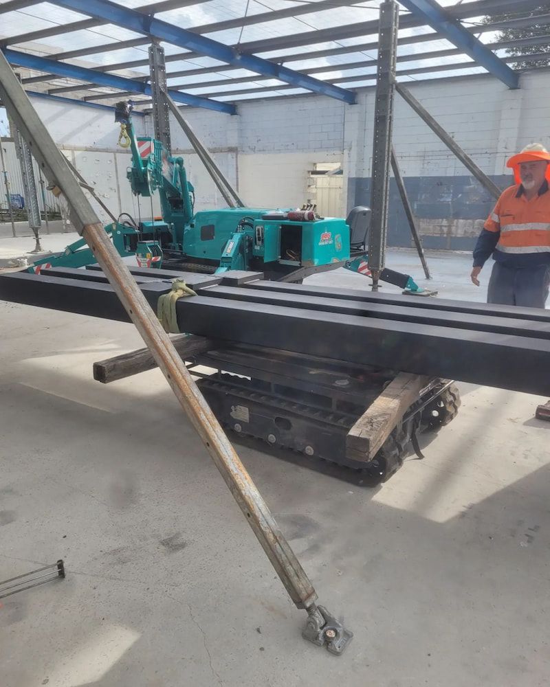 A Man is Next to a Machine That is Lifting a Large Piece of Metal — On The Spot Steel Fabrication in Caloundra West, QLD