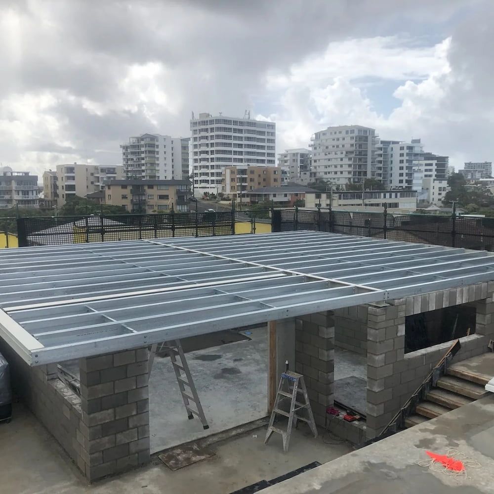 A Metal Roof is Being Built on Top of a Brick Building — On The Spot Steel Fabrication in Caloundra West, QLD