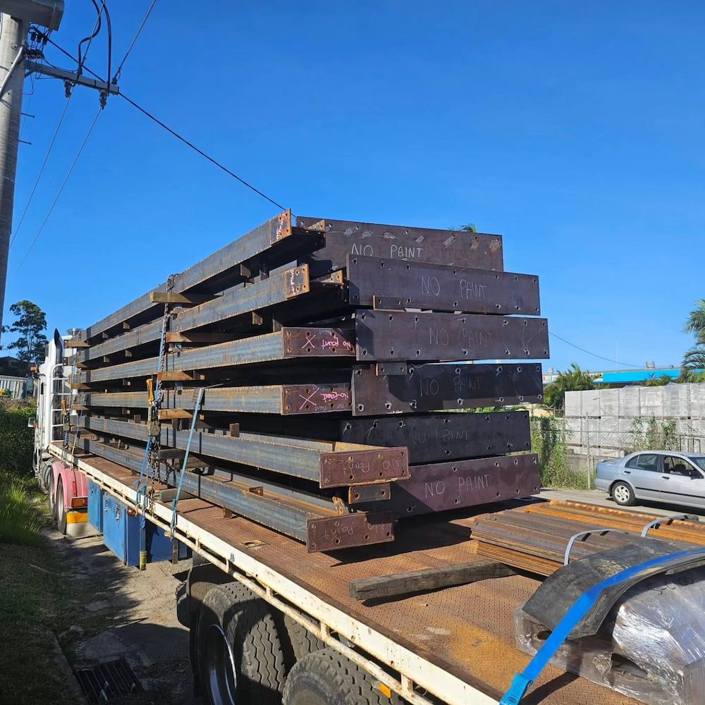 A Truck is Carrying a Large Stack of Steel Beams — On The Spot Steel Fabrication in Caloundra West, QLD