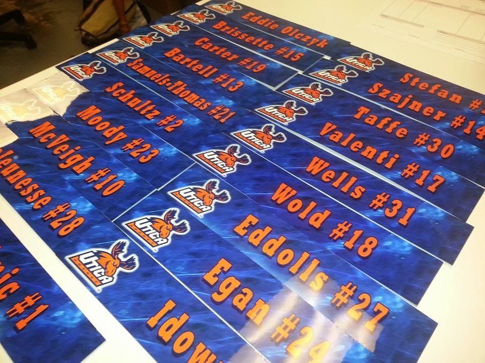 Blue-and-orange sports signs with names and numbers arranged in rows on a table