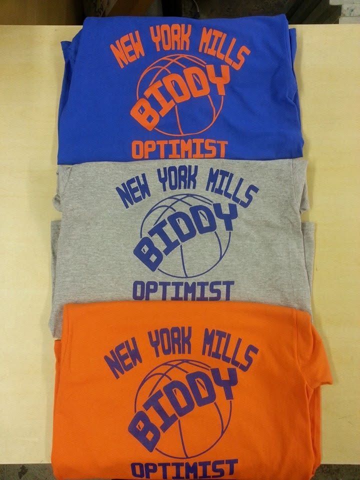 Three folded T-shirts in blue, gray, and orange with “New York Mills Boddy Optimist” text
