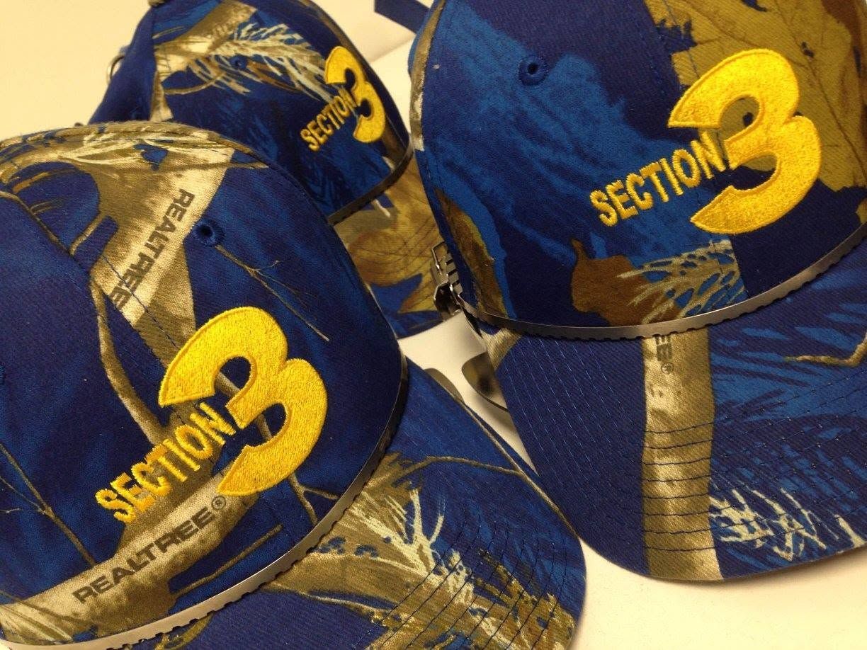 Blue-and-gold Section 3 caps stacked together with a large yellow number 3 logo