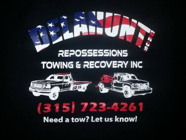 Black Delamonte Repossessions Towing & Recovery Inc. sign with tow trucks and phone number (315) 723-4261