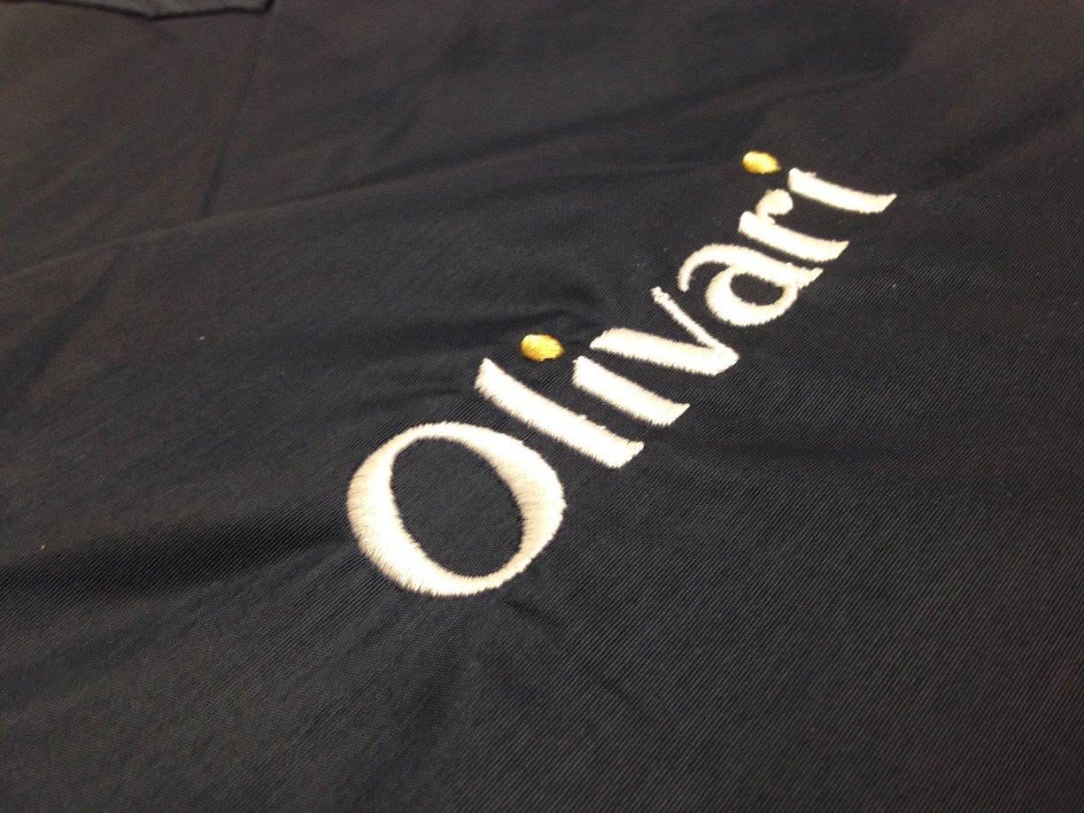 Black shirt with the white word “Olivari” printed diagonally.