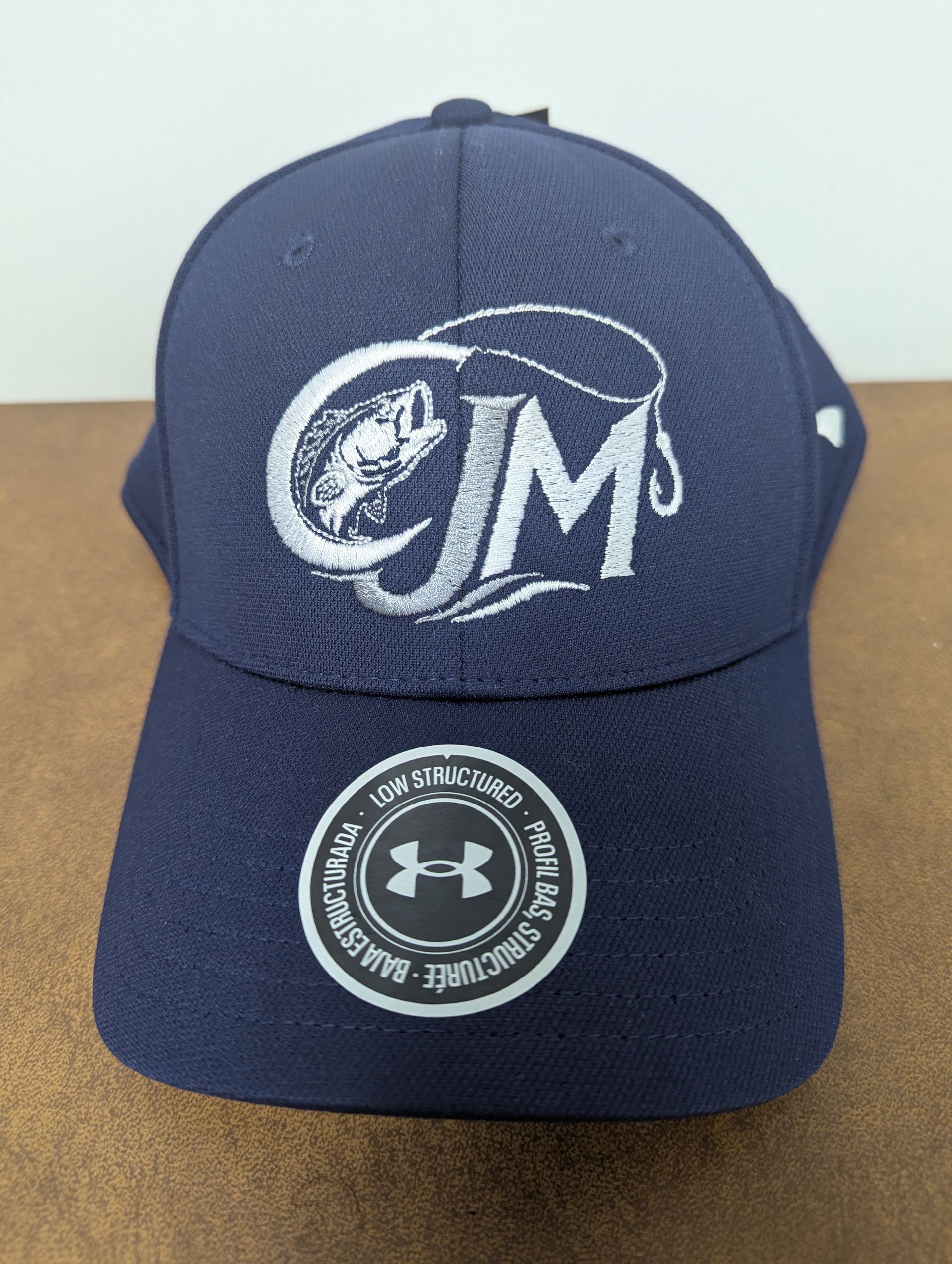 Navy blue Under Armour baseball cap with white embroidered logo on a brown surface