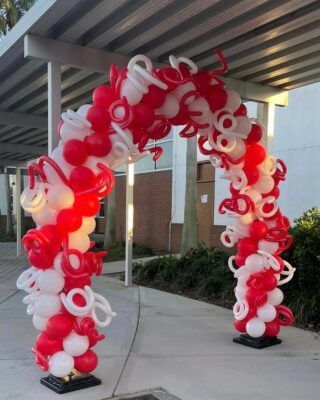 A red and white balloon arch in front of a building