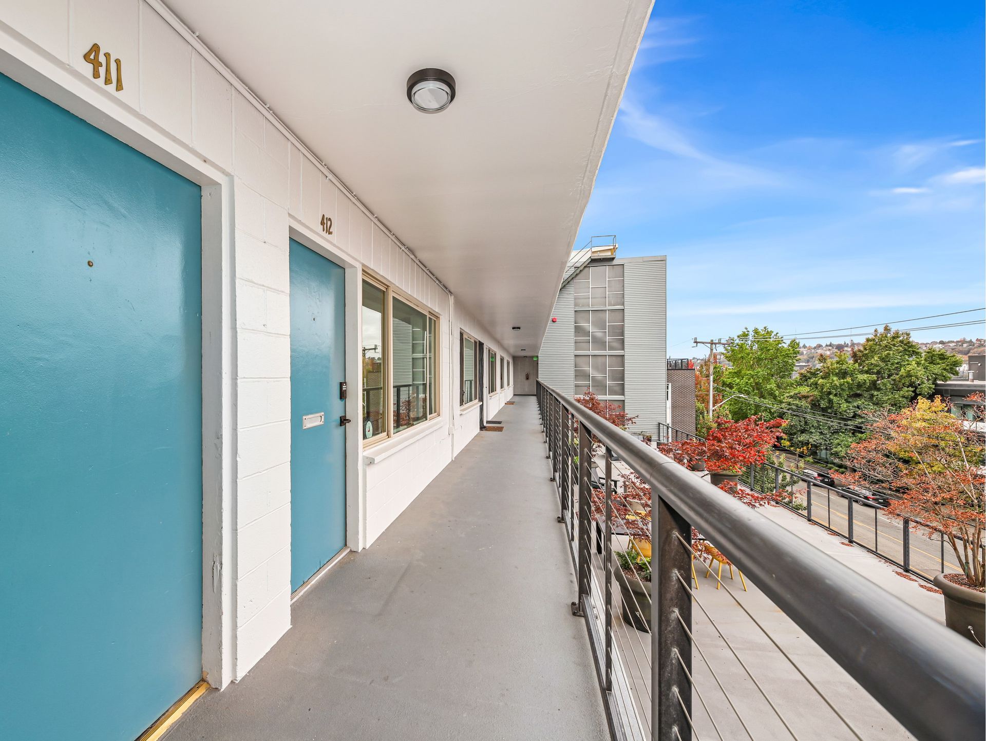 A long hallway between two buildings with blue doors and a balcony.
