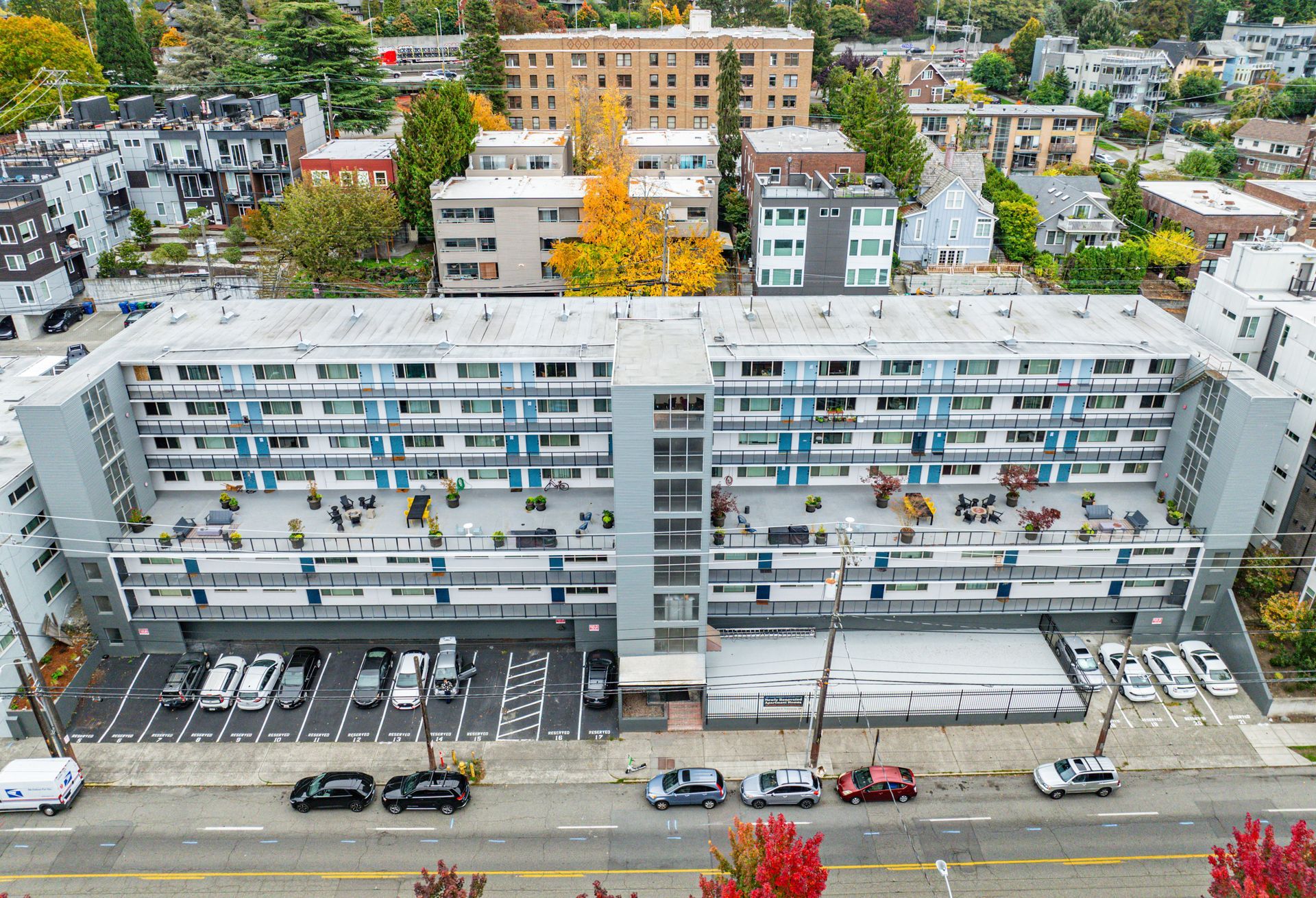 An aerial view of a large apartment building with cars parked in front of it.