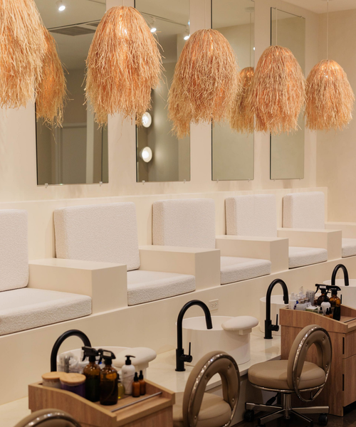 A clean, minimalist nail salon with white cushioned chairs, black fixtures, and decorative hanging straw light fixtures.