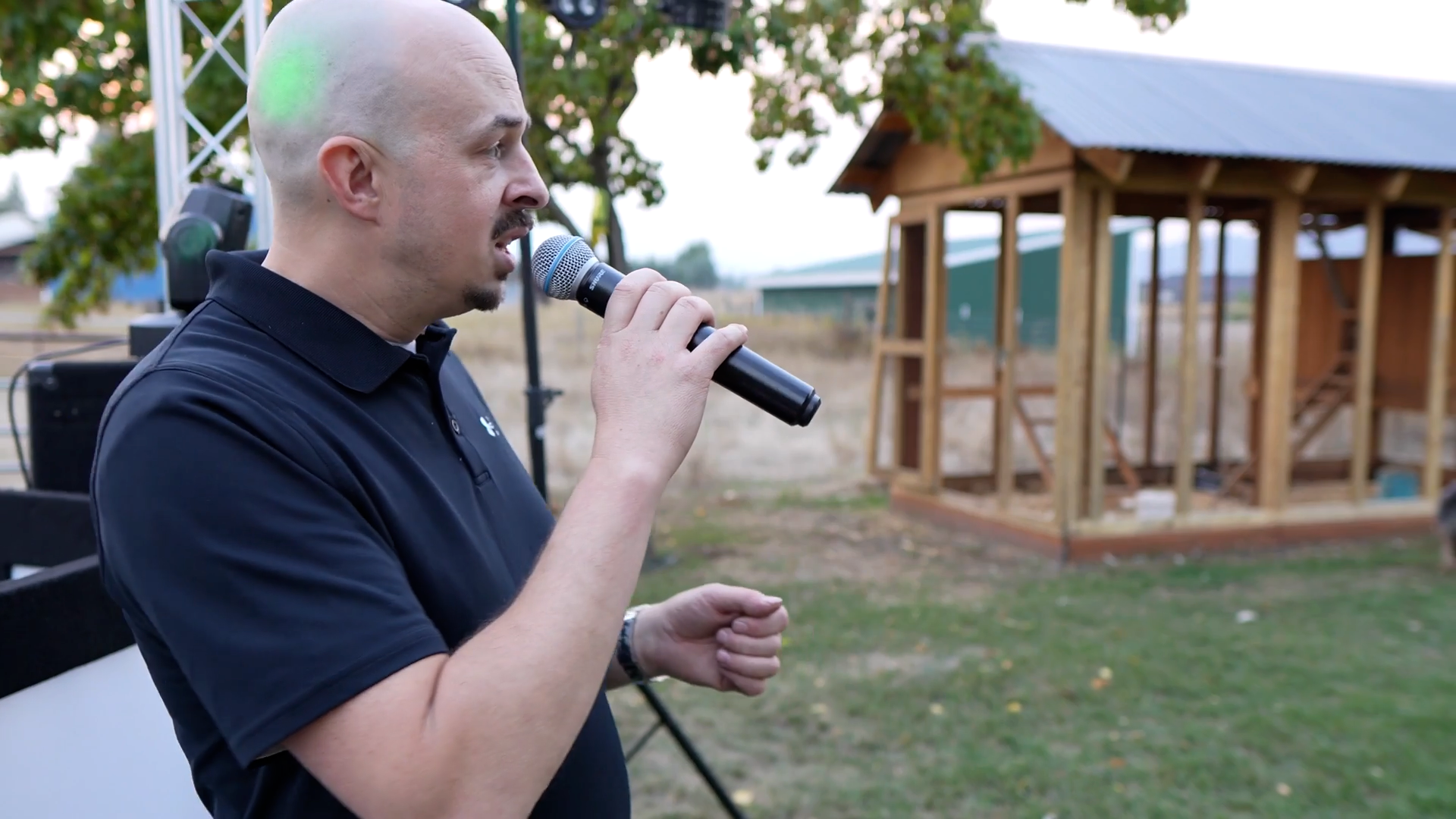Kyle of Cloud and Fire with microphone speaking outdoors, 
