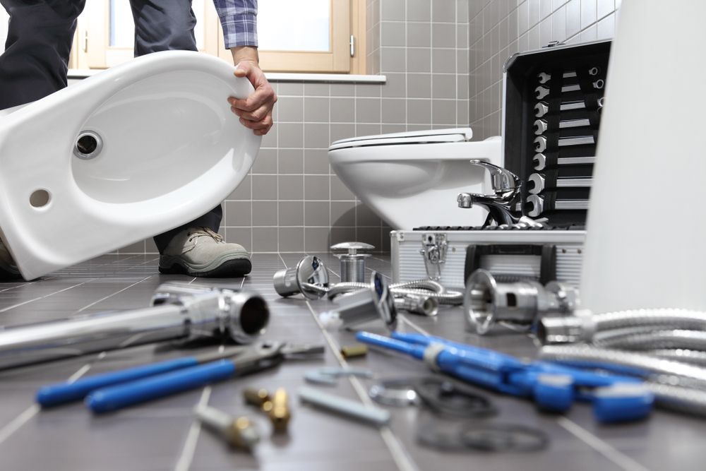 Plumber Installing a Bidet in a Tiled Bathroom, Tools Scattered on the Floor — Pure Plumbing & Electrical in Narromine, NSW