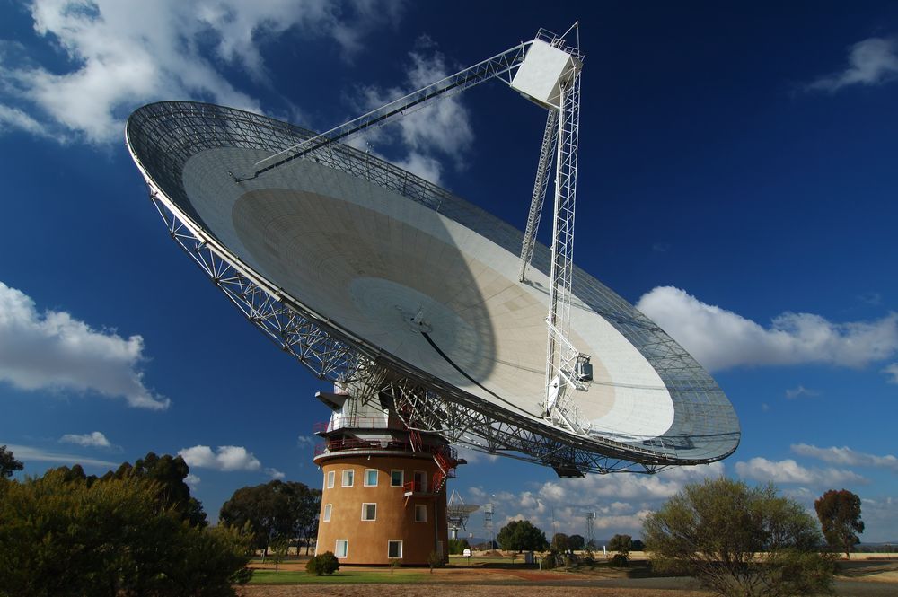Large, Silver Radio Telescope Dish Tilted Against a Bright Blue Sky — Pure Plumbing & Electrical in Parkes, NSW