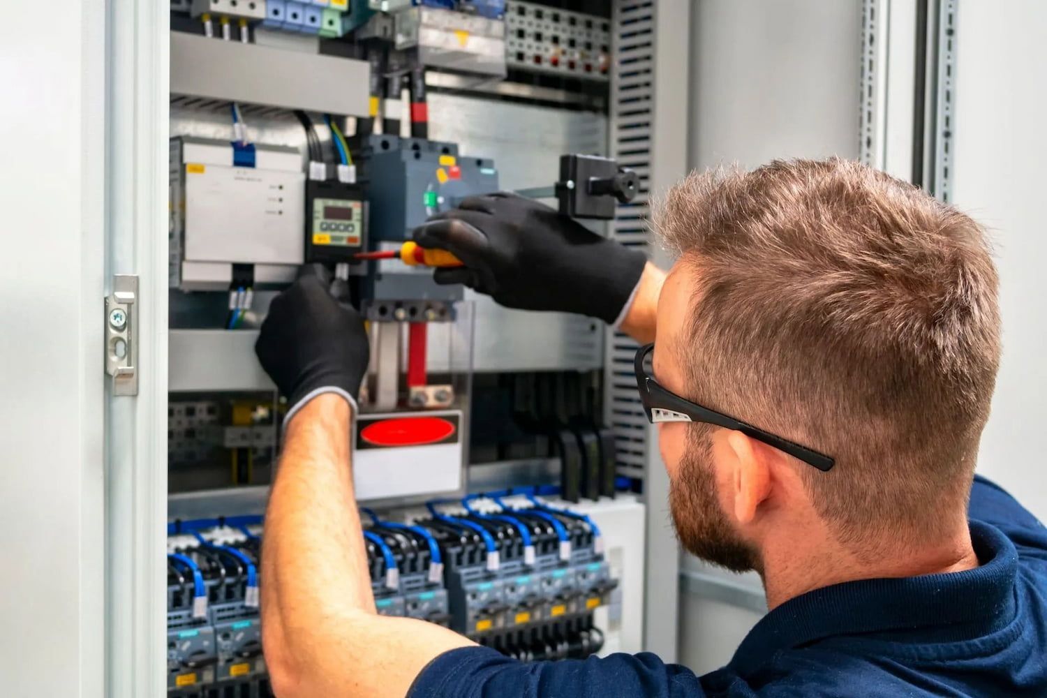 Electrician Wearing Gloves Working on Electrical Panel — Pure Plumbing & Electrical in Dubbo, NSW
