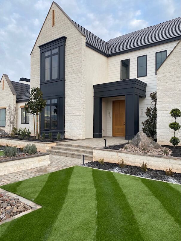 A large white brick house with a lush green lawn in front of it.