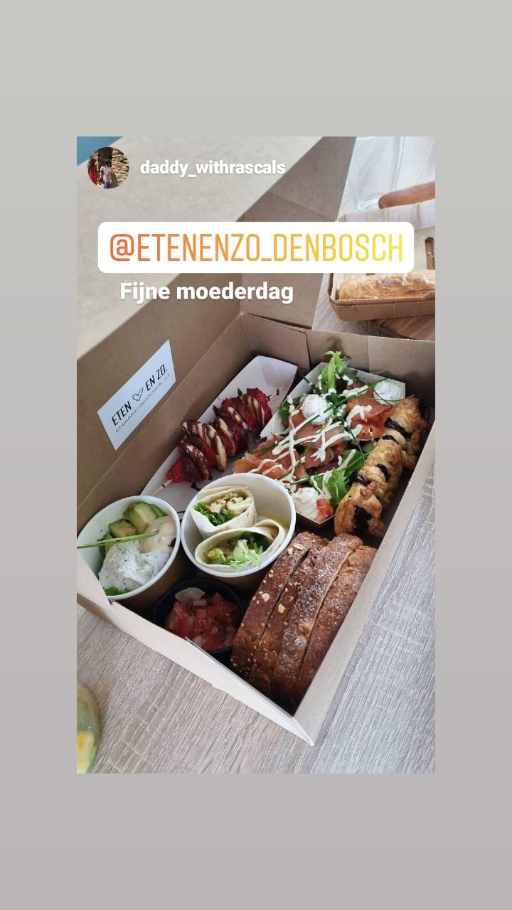 Een kartonnen brunchbox met wraps, een croissant, een broodje, salade en kleine bijgerechten, voorzien van het label 