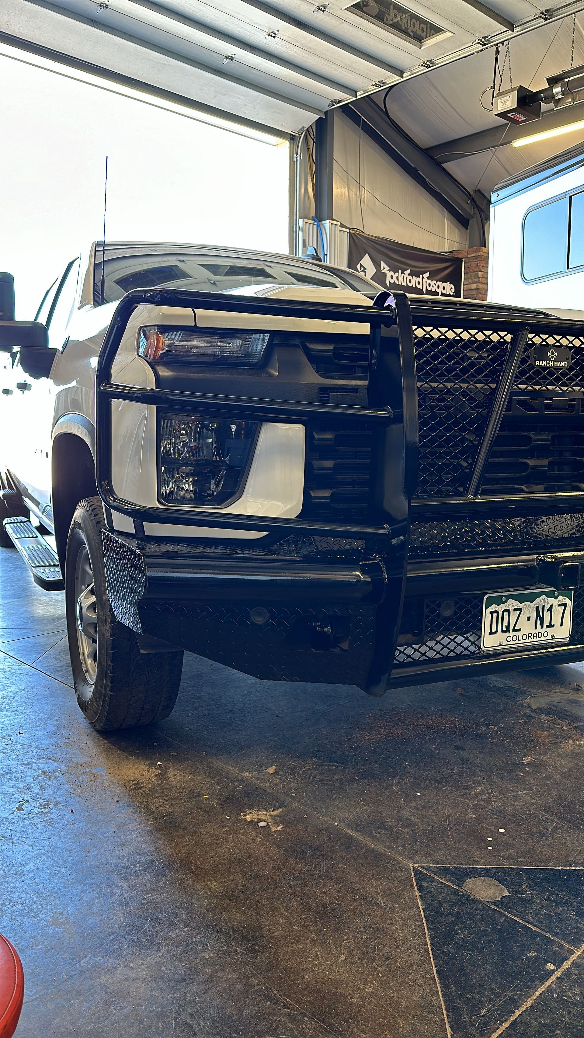 Black pickup truck parked inside a garage with the hood open, front view.