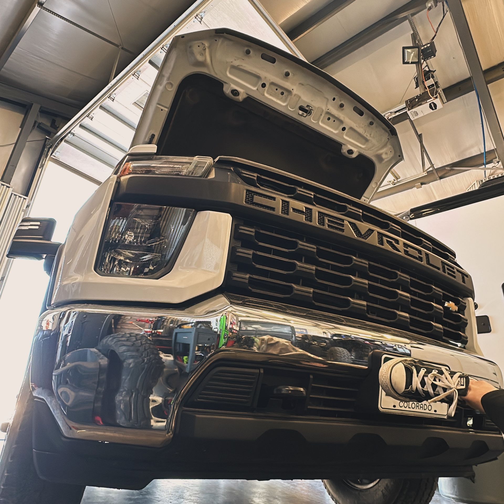 Chevrolet truck with hood open in a garage, front view showing grille and headlights