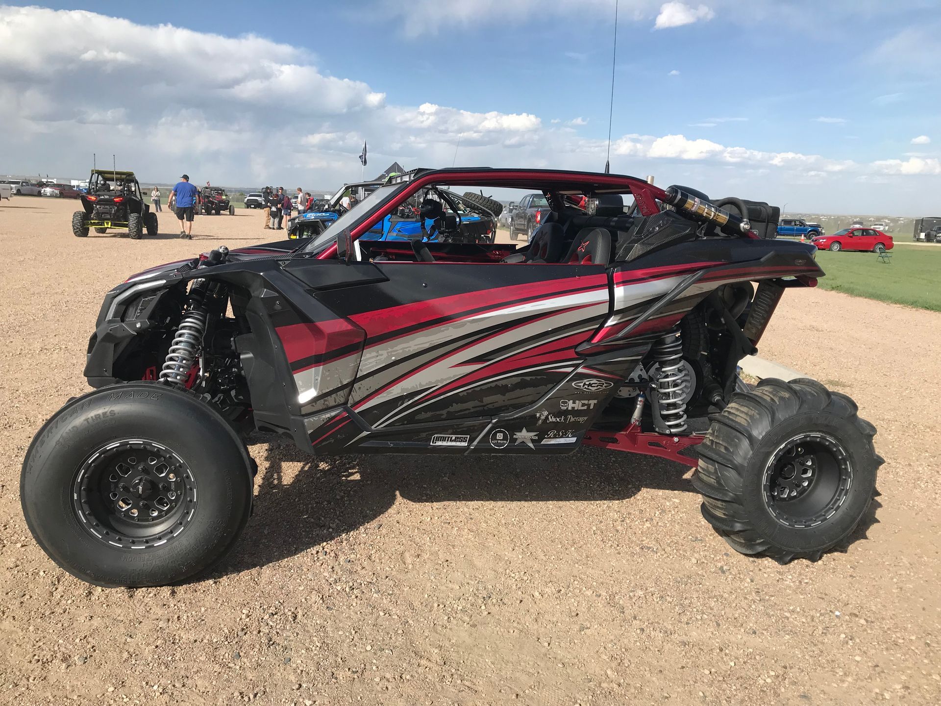 Red and black off-road UTV parked on a gravel lot under a cloudy sky