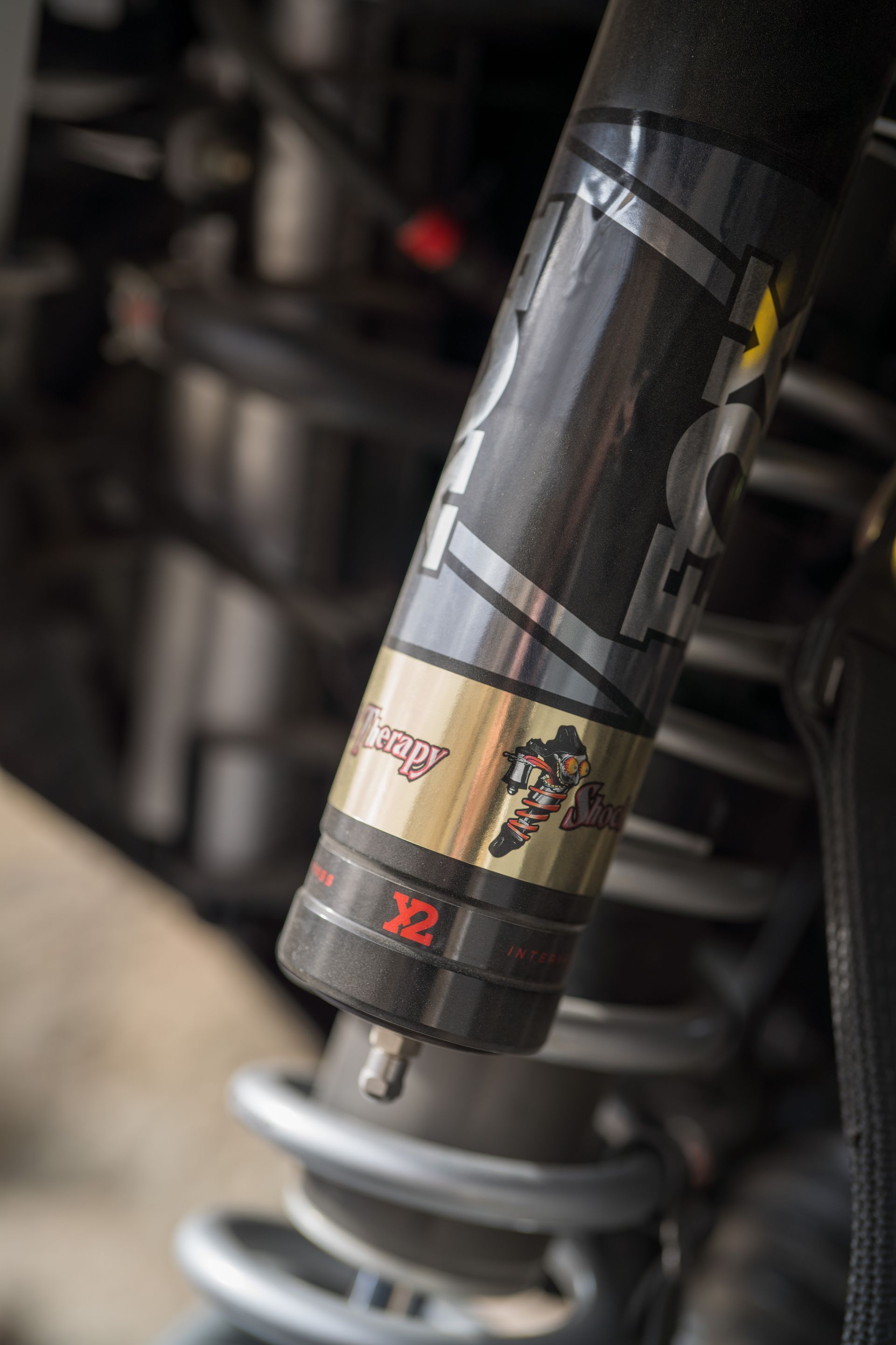 Close-up of a motorcycle rear shock absorber with a white spring and black reservoir.