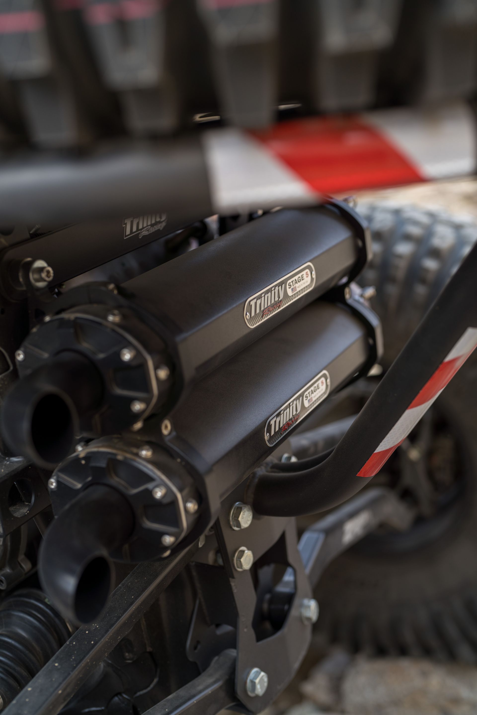 Two black exhaust pipes mounted on a bike or machine, with a red and gray background