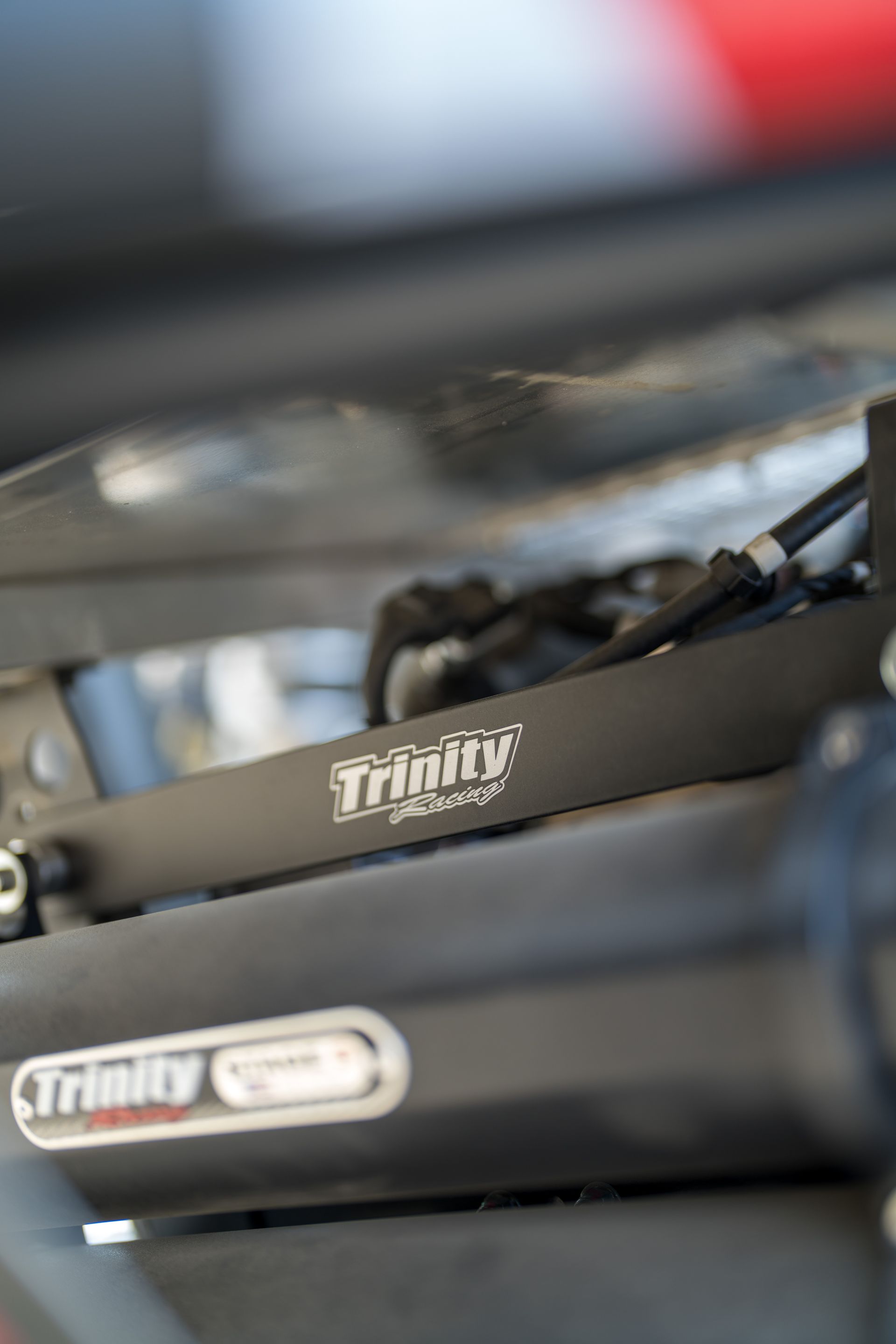 Close-up of black bicycle components with white branding and a blurred red-and-gray background
