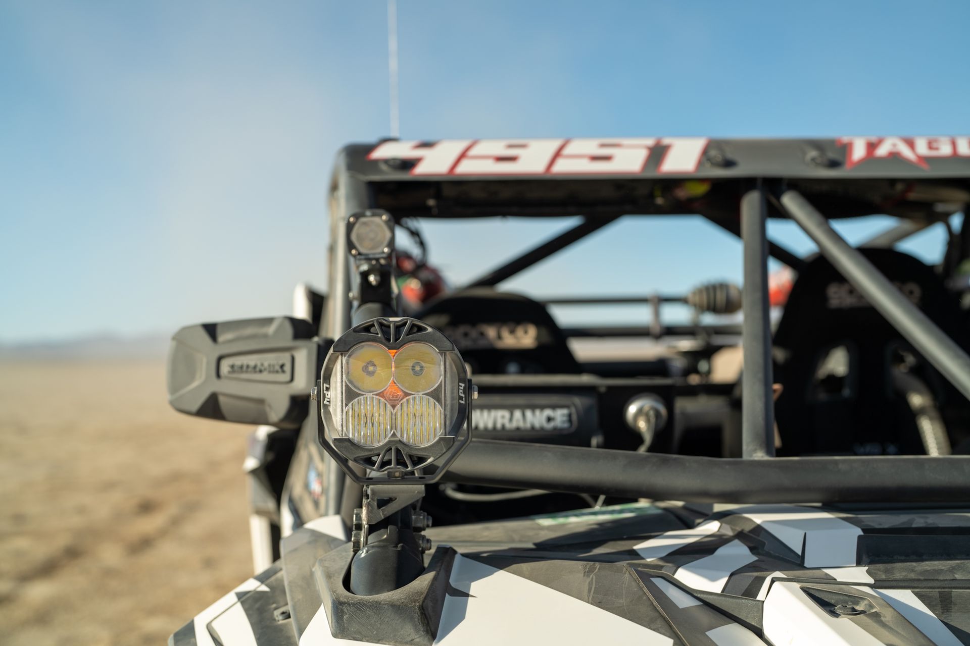 Off-road race buggy close-up on a desert track, with driver visible in the cockpit