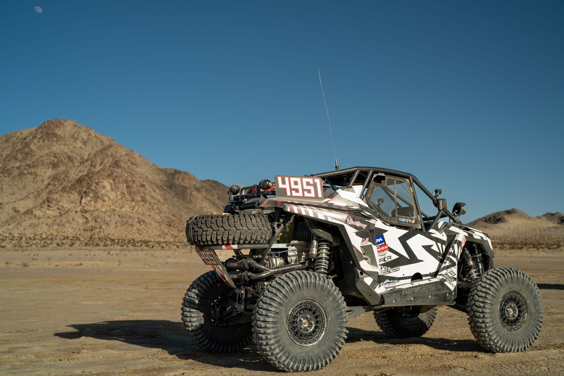 Off-road rock crawler buggy with number 4951 on desert dirt, mountains in background