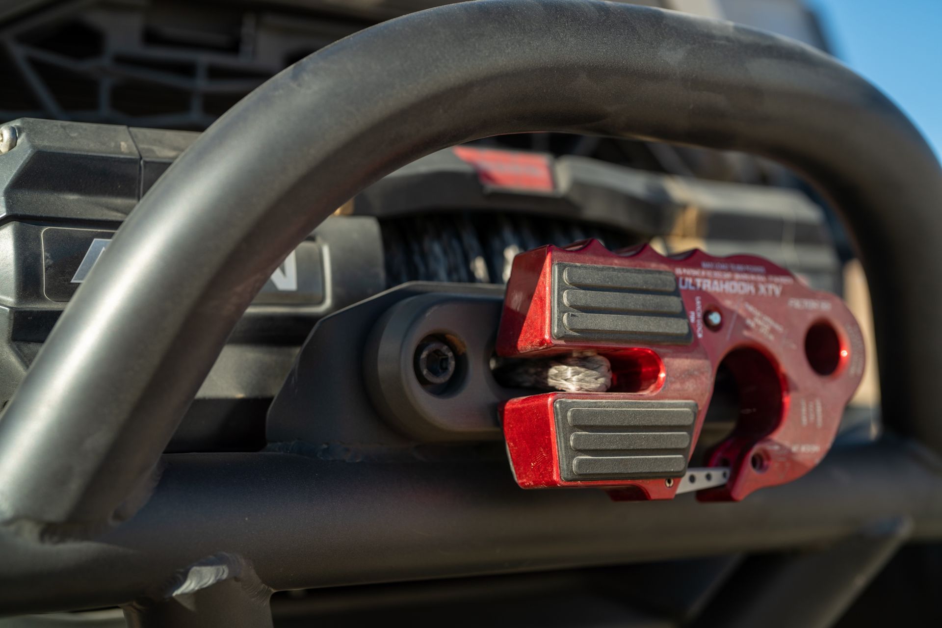 Red bike pedal and crank arm with metal clips in close-up.