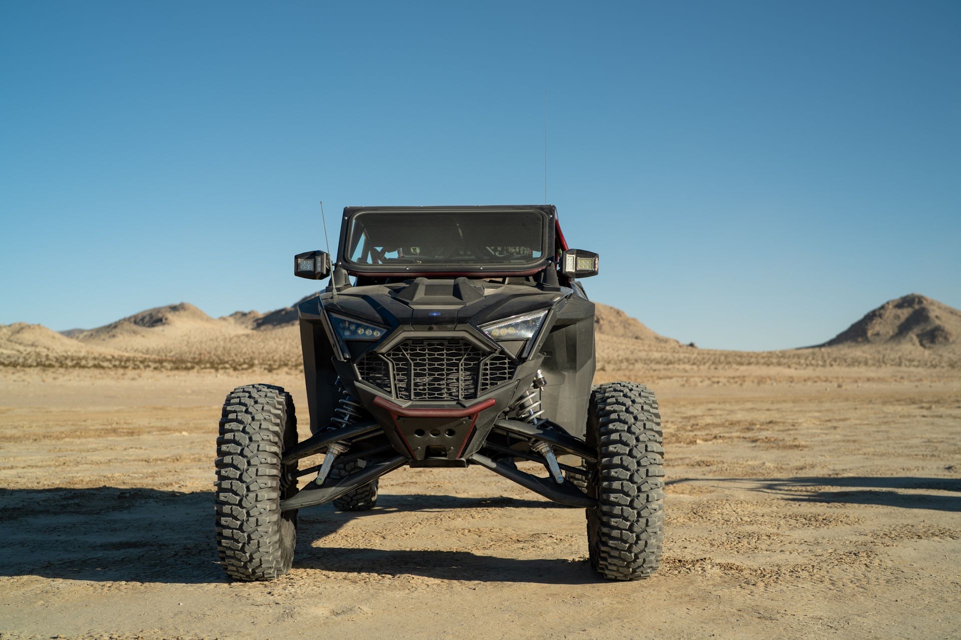 Front view of a black off-road buggy on a desert dirt road under a clear blue sky