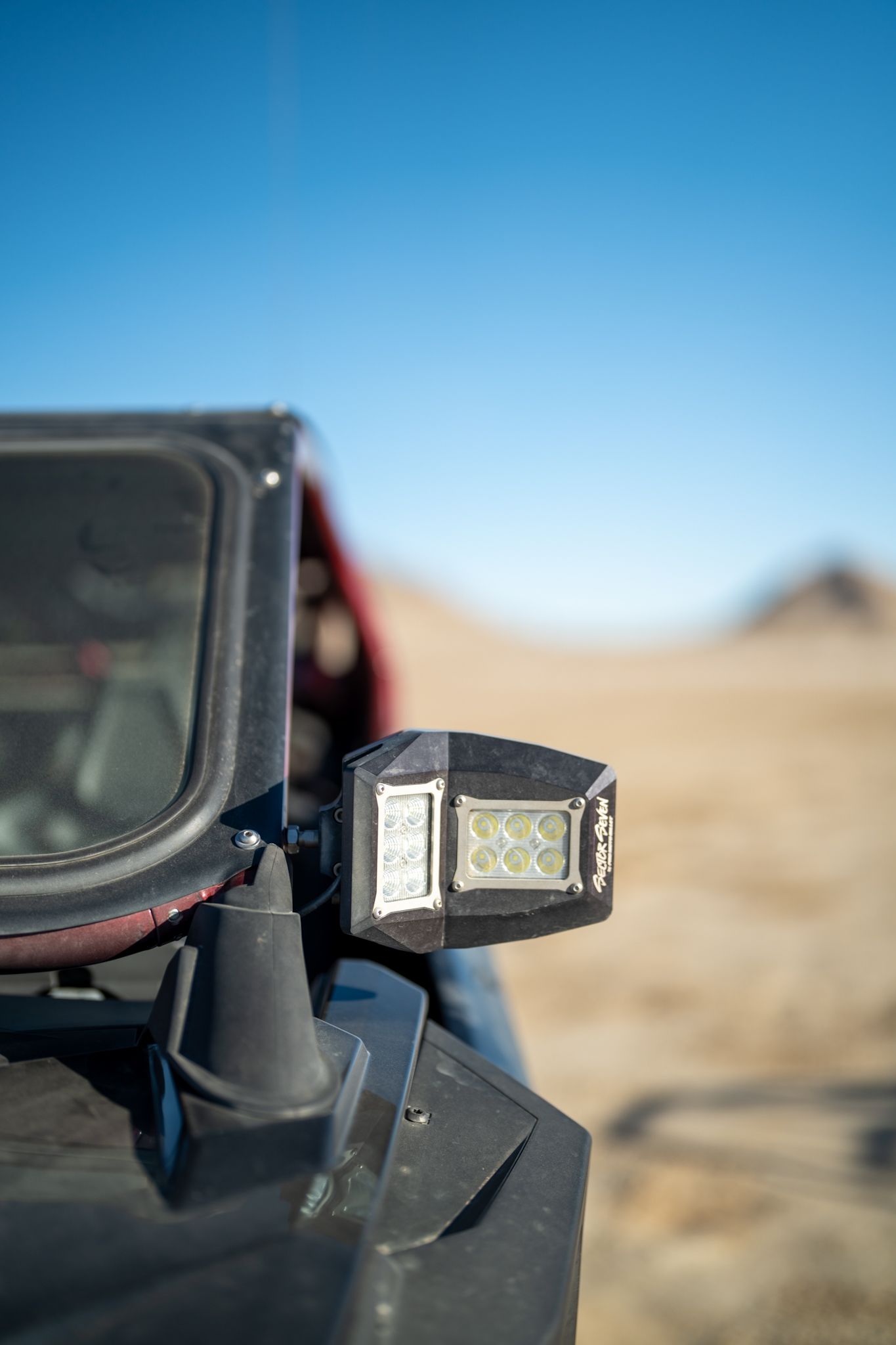 Close-up of a mounted camera or light on a vehicle in a desert under a clear blue sky