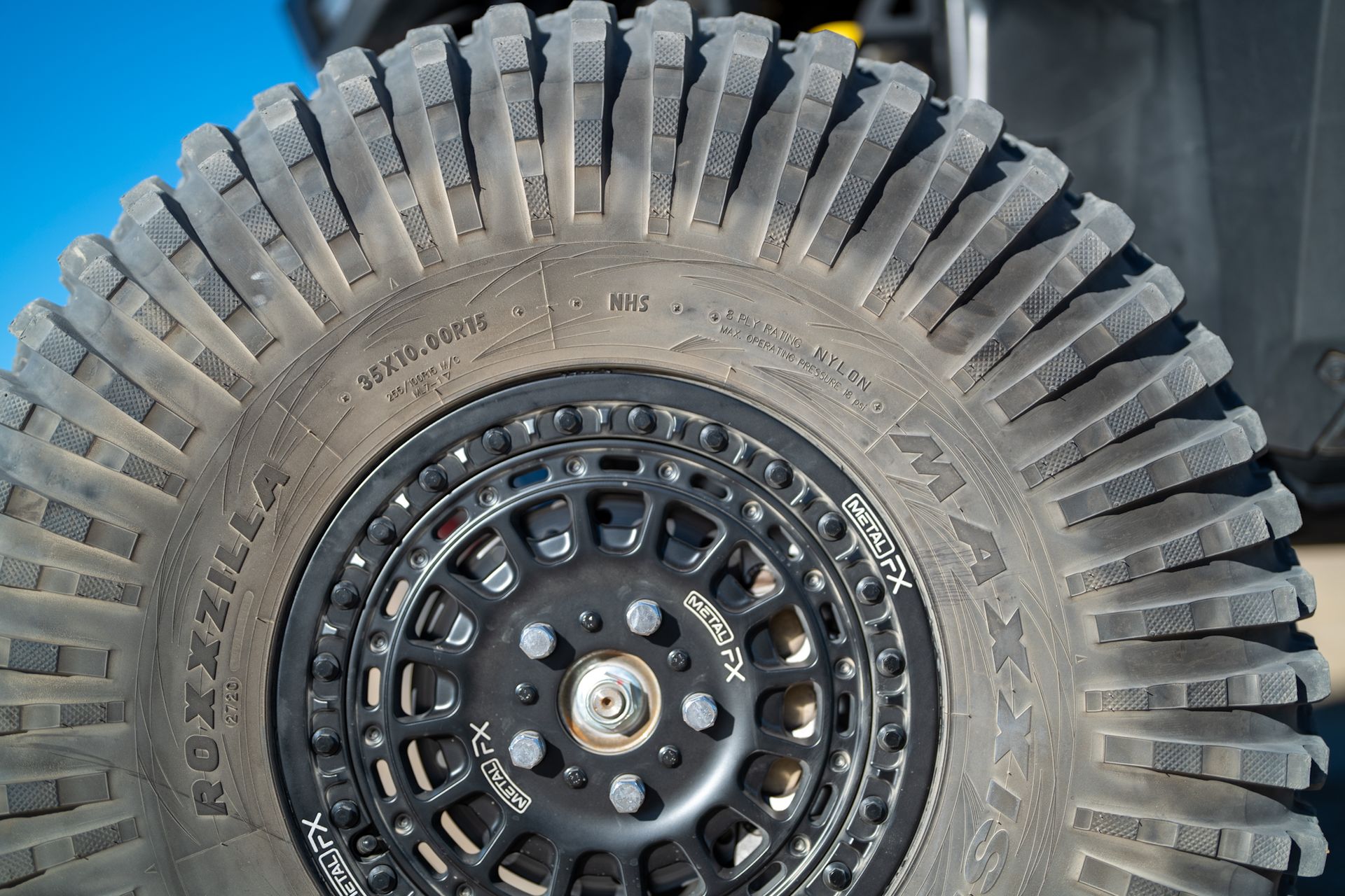 Off-road tire with black rim and deep tread mounted on a vehicle