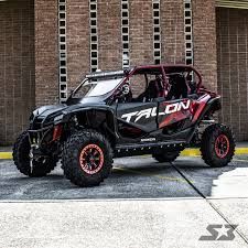 Black off-road UTV with red accents parked in front of a brick wall