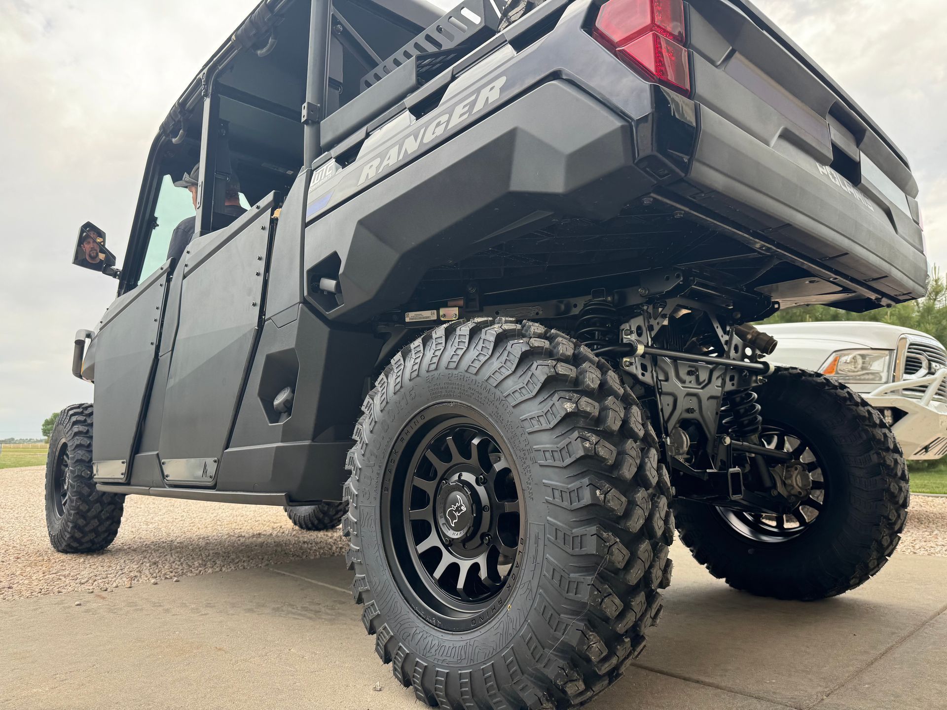 Black off-road utility vehicle with oversized tires parked on pavement, low angle view