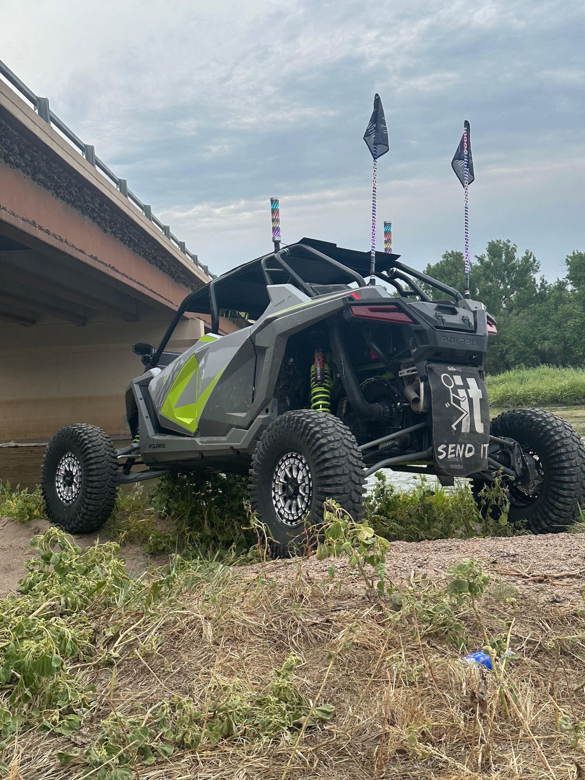 Black off-road buggy on grassy slope beside a building, with flags flying above.