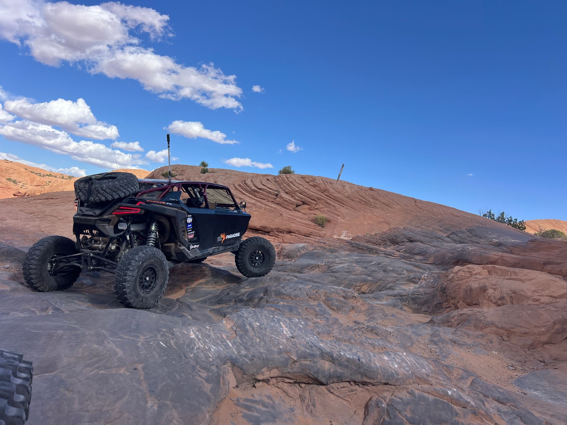 Off-road buggy climbing rocky desert terrain under a blue sky