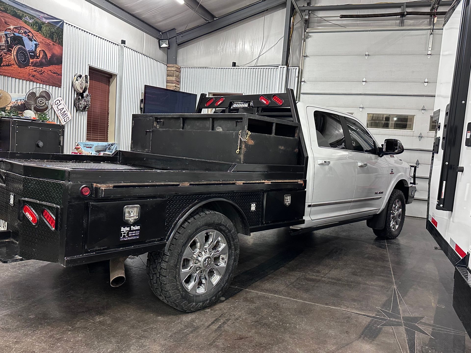 Black and white service truck in a garage with open rear flatbed storage compartments